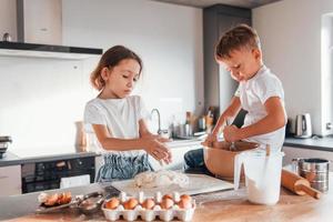 Süßigkeiten machen. kleiner Junge und Mädchen, die Weihnachtsplätzchen in der Küche zubereiten foto