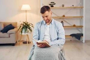 Buch lesen. Behinderter Mann im Rollstuhl ist zu Hause foto