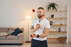 Ein Mann in Freizeitkleidung wirft zu Hause Bälle foto