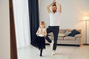 lehren, wie man tanzt. Vater mit seiner kleinen Tochter ist zusammen zu Hause foto