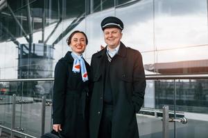 Mann mit Frau. Flugzeugbesatzung in Arbeitsuniform ist draußen auf dem Flughafen zusammen foto
