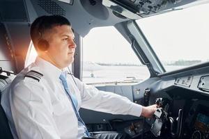 Seitenansicht. Pilot in formeller Kleidung sitzt im Cockpit und steuert Flugzeug foto