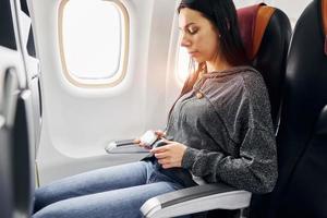 Junge Frau in Freizeitkleidung sitzt auf dem Beifahrersitz im Flugzeug foto