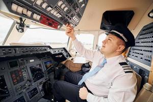 professioneller Arbeiter. Pilot in formeller Kleidung sitzt im Cockpit und steuert Flugzeug foto