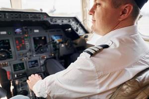 ruhige Atmosphäre. Pilot in formeller Kleidung sitzt im Cockpit und steuert Flugzeug foto