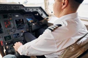 ruhige Atmosphäre. Pilot in formeller Kleidung sitzt im Cockpit und steuert Flugzeug foto