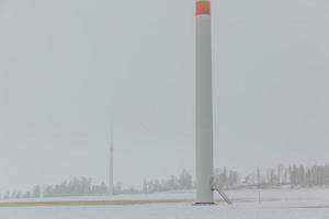 Basis eines Windturbinenmastes mit Treppe zum Eingang auf dem Windmühlenpark in nebliger Winterlandschaft foto