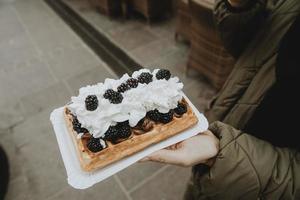 Detail der traditionellen polnischen Spezialität Gofry mit Schlagsahne und Brombeeren auf Frauenhand foto