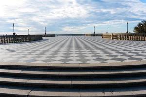 livorno, italien-27. november 2022-menschen, die an einem sonnigen tag auf der mascagni-terrasse spazieren, einer herrlichen belvedere-terrasse mit schachbrettgepflasterter oberfläche, livorno, toskana, italien. foto