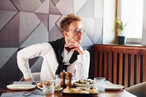 Mann mit Brille sitzt am Tisch. drinnen des neuen modernen luxusrestaurants foto