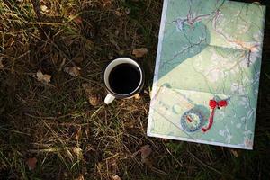 Draufsicht auf Karte, Kompass und Tasse Getränk auf dem Rasen foto