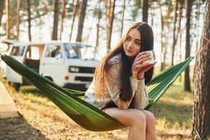 sitzt auf der Hängematte. Frau ist im Sommer tagsüber allein im Wald unterwegs foto