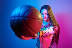 in Basketballuniform. modische junge frau, die im studio mit neonlicht steht foto