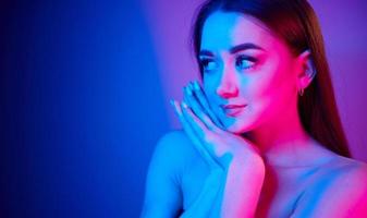 Nahaufnahme. modische junge frau, die im studio mit neonlicht steht foto