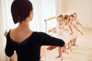 Trainer unterrichtet Kinder. kleine Ballerinas bereiten sich auf den Auftritt vor, indem sie Tanzbewegungen üben foto