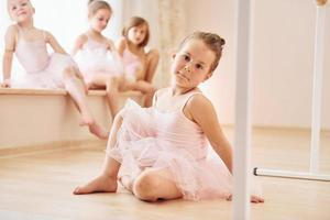 Mädchen sitzt auf der Fensterbank und auf dem Boden. kleine ballerinen, die sich auf die leistung vorbereiten foto