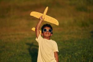 mit Pilotenbrille. afroamerikanisches kind hat tagsüber im sommer spaß auf dem feld foto