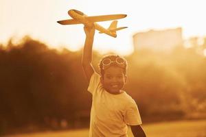 mit Pilotenbrille. afroamerikanisches kind hat tagsüber im sommer spaß auf dem feld foto