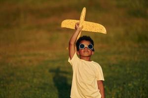 mit Pilotenbrille. afroamerikanisches kind hat tagsüber im sommer spaß auf dem feld foto