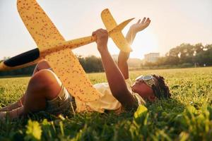 Junge mit Spielzeugflugzeug. afroamerikanisches kind hat tagsüber im sommer spaß auf dem feld foto