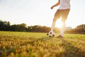 läuft mit Ball. junge Fußballspieler trainieren auf dem sportlichen Feld foto