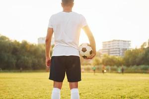 Stehen und Ball in der Hand halten. junge Fußballspieler trainieren auf dem sportlichen Feld foto