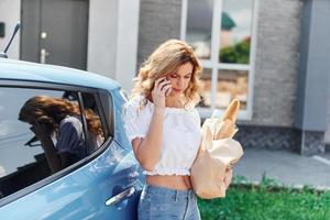 Halten von Produkten in der Tasche. Junge Frau in Freizeitkleidung mit ihrem Elektromobil tagsüber im Freien foto