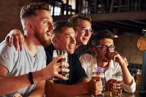 mit Bier in der Hand. Menschen in Freizeitkleidung sitzen in der Kneipe foto