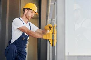 Seitenansicht. junger mann, der tagsüber in uniform auf dem bau arbeitet foto