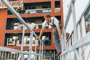 Gebäude außen. junger mann, der tagsüber in uniform auf dem bau arbeitet foto