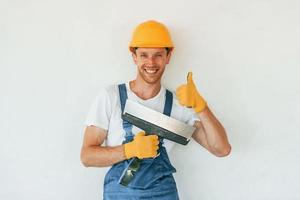 saubere Wände. junger mann, der tagsüber in uniform auf dem bau arbeitet foto