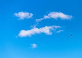 blauer Himmel mit weißen, flauschigen, gesichtsförmigen Wolken foto