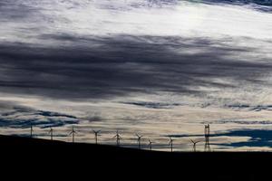 grüne nachhaltige energie windmühle power turbine stromgeneratoren auf sanften hügeln mit wolken und blauem himmel foto
