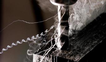 Bridgeport-CNC-Schaftfräser, der einen Stapel Stahlplatten mit Metallspänen und mäßigem Rauch nachzieht foto