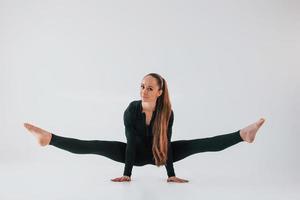 in schwarzer Kleidung. junge frau in sportlicher kleidung, die drinnen turnt foto