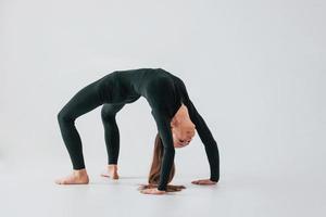 vor weißem Hintergrund. junge frau in sportlicher kleidung, die drinnen turnt foto