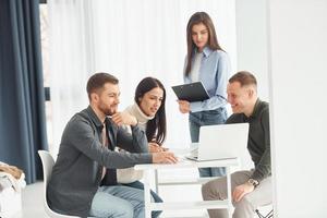 Vier Personen arbeiten im Büro, indem sie drinnen am Tisch sitzen foto