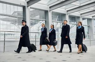 Flugzeugbesatzung in Uniform geht gemeinsam zur Arbeit foto