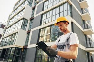 moderne Stadt. junger mann, der tagsüber in uniform auf dem bau arbeitet foto