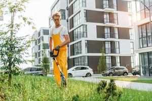 moderne Gebäude. mann mähte das gras mit rasenmäher draußen im hof foto