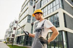 moderne Stadt. junger mann, der tagsüber in uniform auf dem bau arbeitet foto