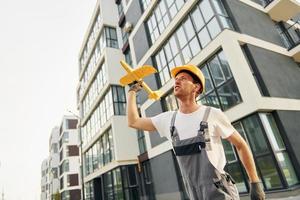 moderne Stadt. junger mann, der tagsüber in uniform auf dem bau arbeitet foto