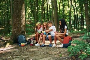 eine Pause machen. kinder, die mit reiseausrüstung im wald spazieren gehen foto