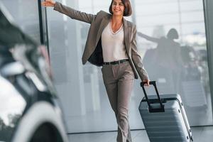 glückliche Frau mit Gepäck steht drinnen. Konzeption des Tourismus foto