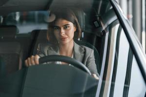 Vorderansicht. Frau testet neues Auto. drinnen sitzen in modernen autos foto