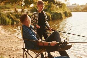 sonniges Wetter. Vater und Sohn beim gemeinsamen Angeln im Freien im Sommer foto