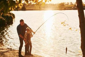 mit Fang. Vater und Sohn beim gemeinsamen Angeln im Freien im Sommer foto