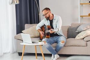 Songwriting-Prozess. Mann in Freizeitkleidung und mit Akustikgitarre ist drinnen foto