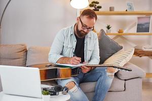 Vorstellung von Kreativität. Mann in Freizeitkleidung und mit Akustikgitarre ist drinnen foto