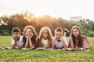 Vorderansicht. Eine Gruppe glücklicher Kinder ist tagsüber draußen auf dem Sportplatz foto